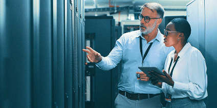 Data center technicians collaborating and checking server hardware with a digital tablet.