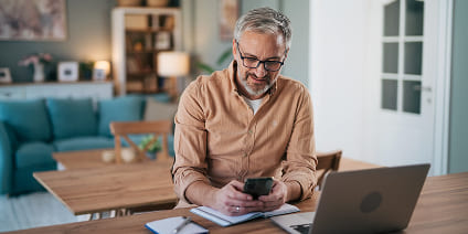 Man with glasses texting on his smartphone while working from home.