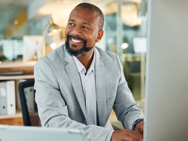 A male professional working at a desk in a bright office environment.