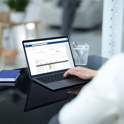 Person using a laptop displaying a financial dashboard at a desk.
