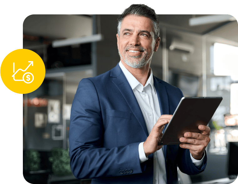 Businessman in a blue suit holding a tablet with a financial growth icon nearby.