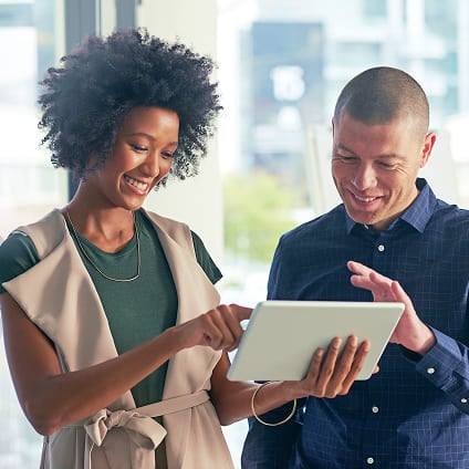 Man and woman collaborating and smiling over a digital tablet device.