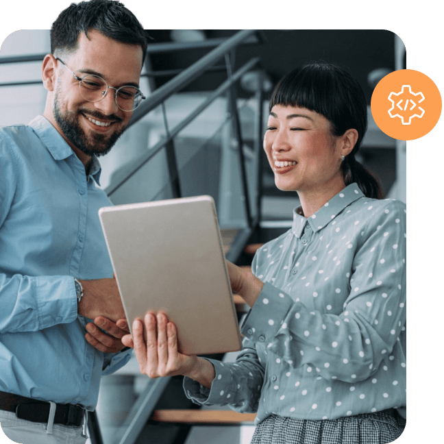 Two colleagues looking at a tablet with an orange developer icon overlay