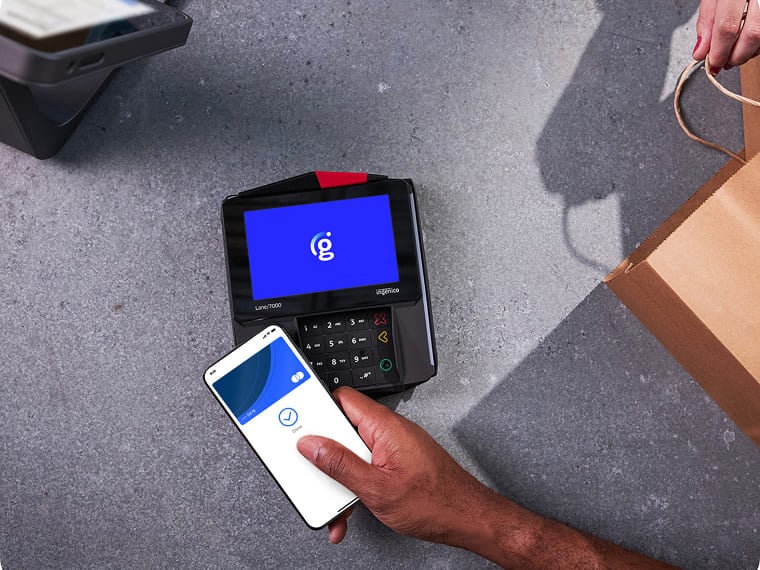 A person making a contactless mobile payment next to a shopping bag