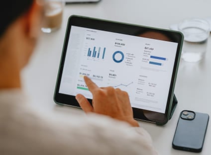 Person touching a tablet screen displaying financial analytics and charts.