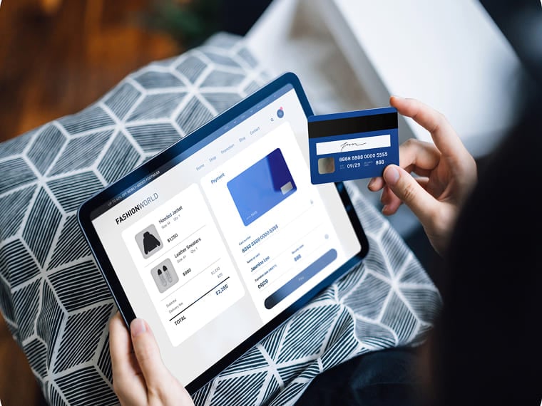Person holding a credit card while shopping online on a tablet