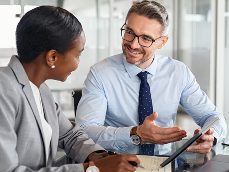 Two business professionals reviewing information on a tablet at a desk.