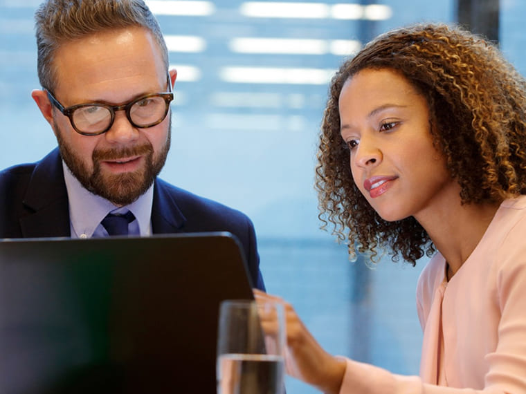 Two business colleagues reviewing content together on a laptop screen