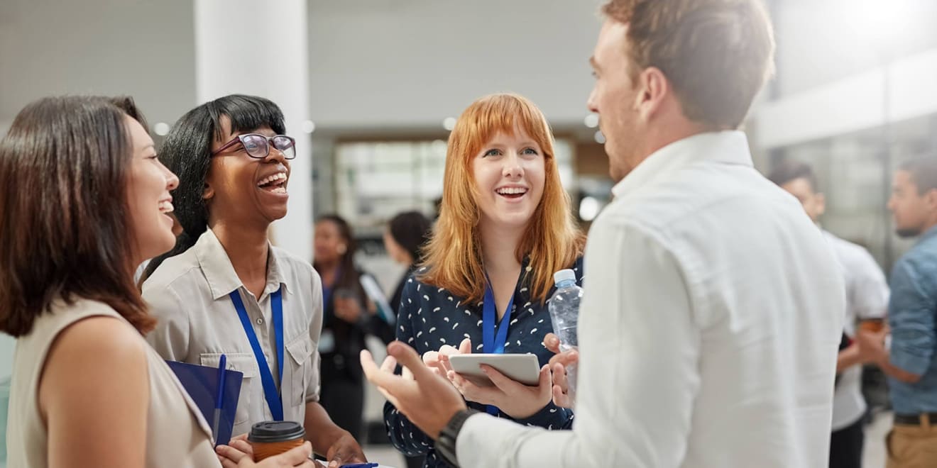 A group of diverse colleagues laughing and talking at a corporate networking event