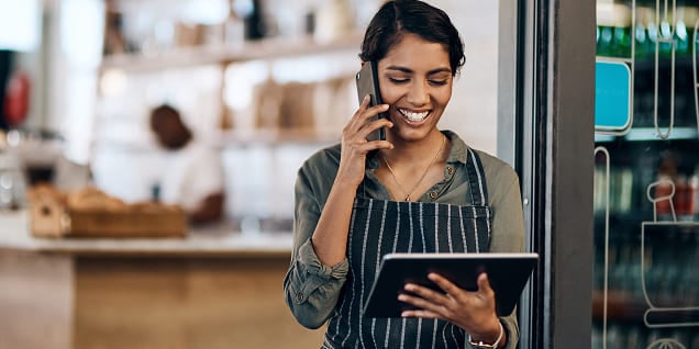 Smiling café worker talking on the phone while holding a table