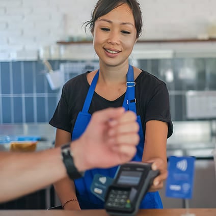 Customer paying with a smartwatch using a POS terminal held by a cashier.