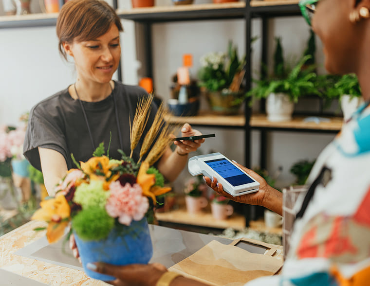 Customer making a contactless payment using a phone in a flower shop.