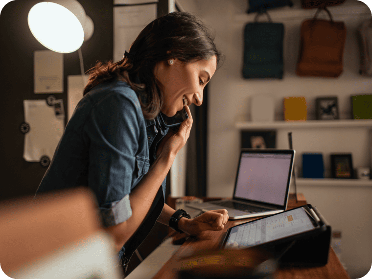Small business owner speaks on phone with customer support to get help with technology.