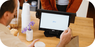 A customer buying coffee and pastries at a POS terminal checkout counter in a café.