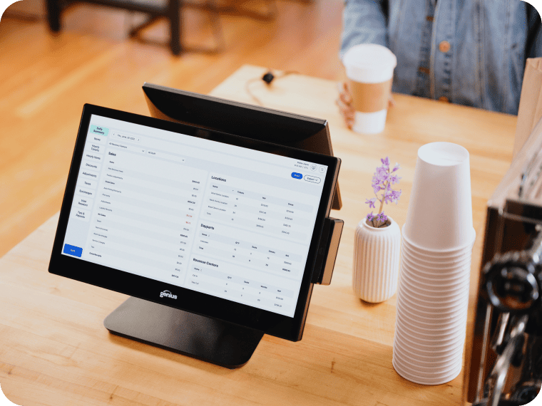 Point-of-sale terminal screen showing sales reports on a coffee shop counter.