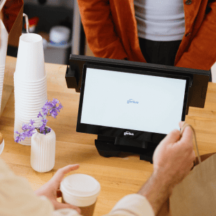 A barista takes a payment on a Genius countertop point of sale system.