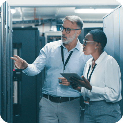 Two IT specialists inspecting server racks with a tablet in a modern data center.