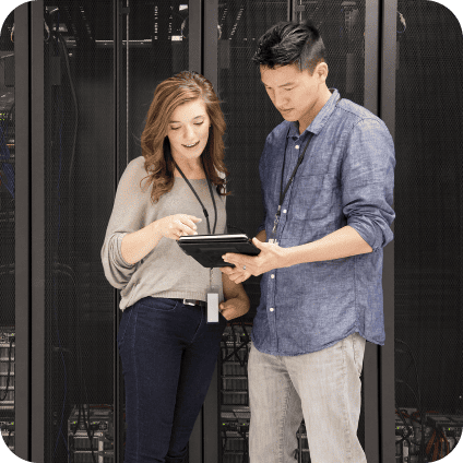 Two IT technicians looking at a tablet together in a server room.