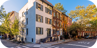 A picture of a row of properties, including a white building and apartments with brick exterior.