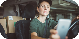A woman making deliveries sits in a parked delivery truck inside a parking garage.