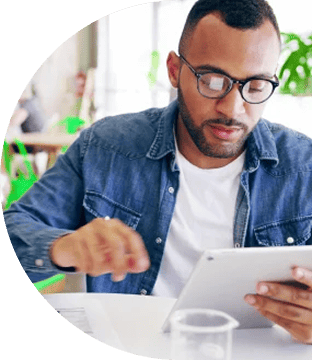 Professional man with glasses reviewing information on a tablet.