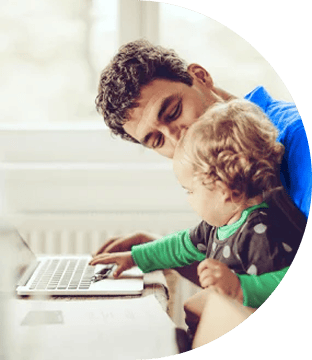 Man holding a young child who is reaching out to touch a laptop keyboard.