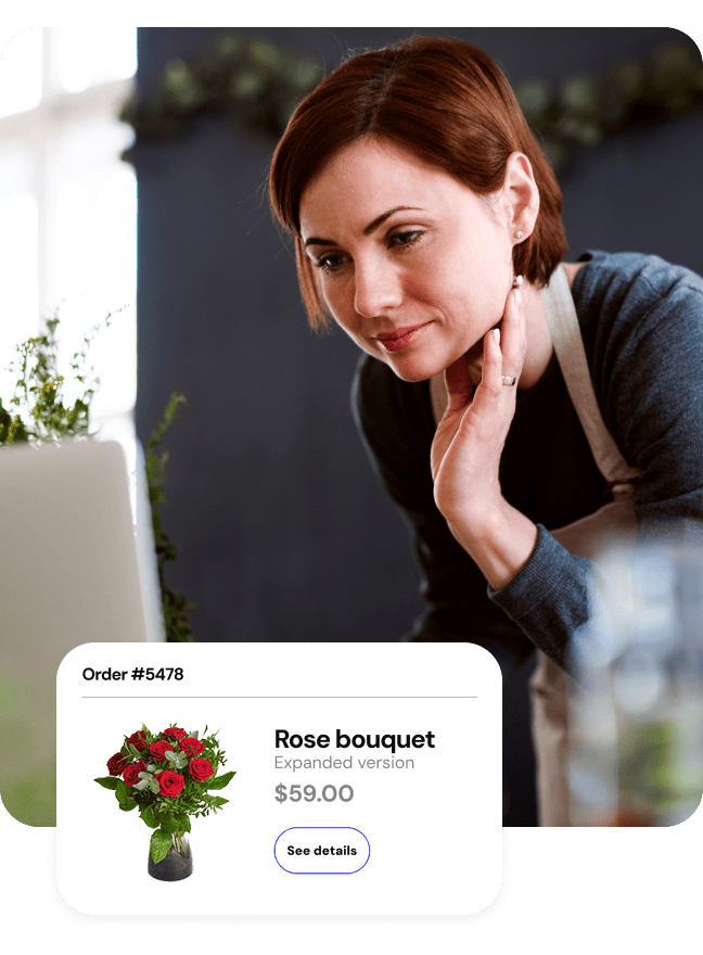 Woman in an apron reviewing an online flower order popup on her laptop in a florist shop.