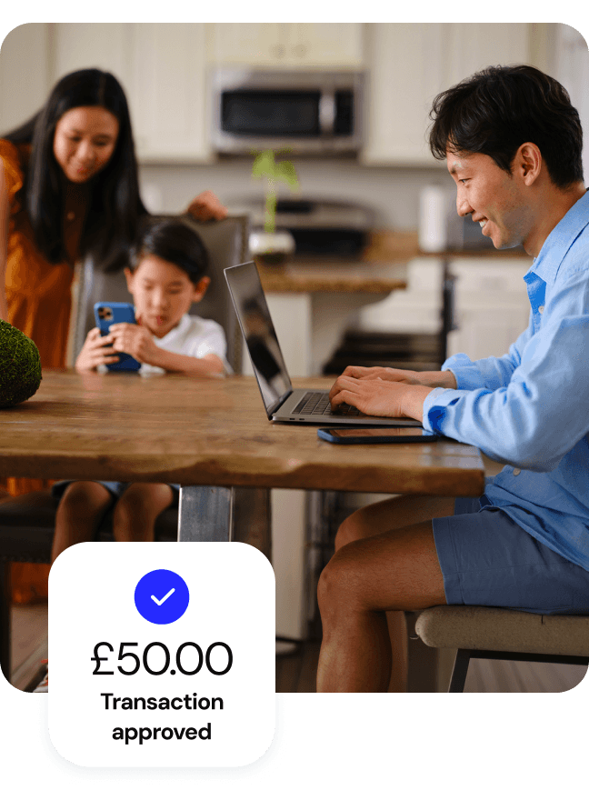 Man using a laptop at home with a "£50.00 Transaction approved" notification graphic.