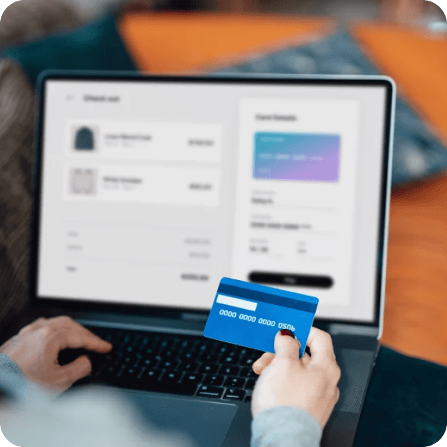 Person holding a blue credit card while completing an online checkout.