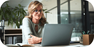 Une femme active portant des lunettes travaille sur un ordinateur portable à son bureau.