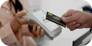 Un client présente une carte de crédit noire sur un terminal de paiement sans fil tenu par un caissier.