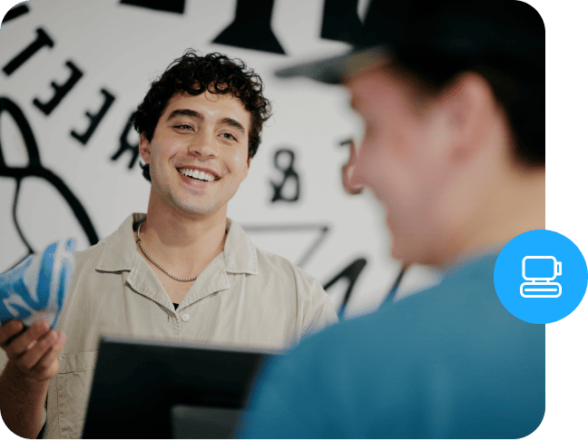 A smiling store employee talking to a customer over a POS counter.