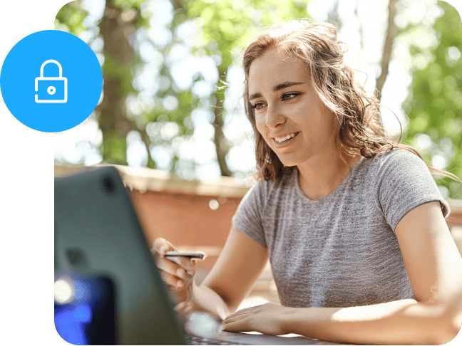 Woman using a laptop outdoors with a card, featuring a blue security lock icon.