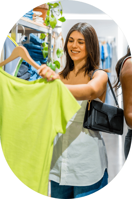 Woman holding up a lime green shirt while shopping for clothes at a retail store.