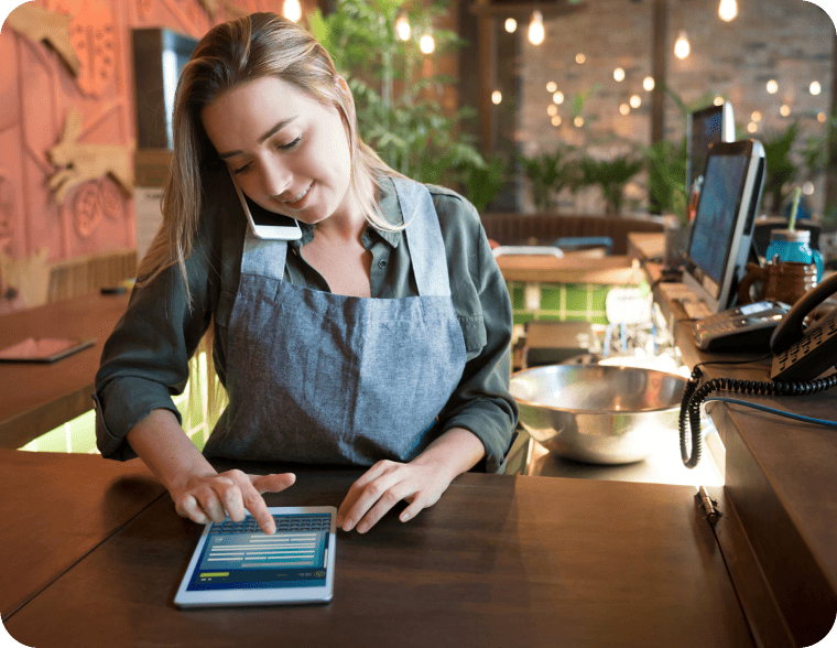 Restaurant employee multitasking with a mobile phone and tablet computer.