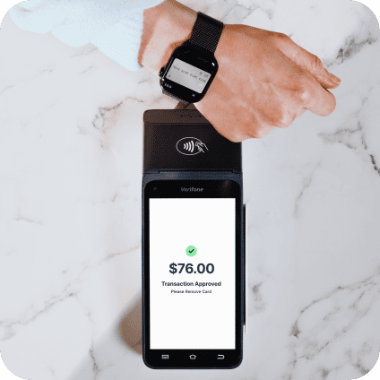 Closeup of a person tapping their smartwatch digital wallet on a black mobile payment terminal to pay