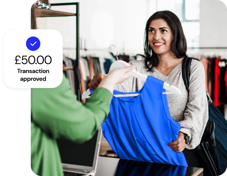 A woman smiles as she buys a blue sleeveless top in a clothing store for fifty dollars.