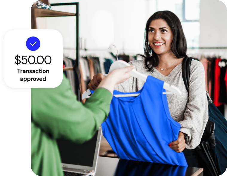A woman smiles as she buys a blue sleeveless top in a clothing store for fifty dollars.