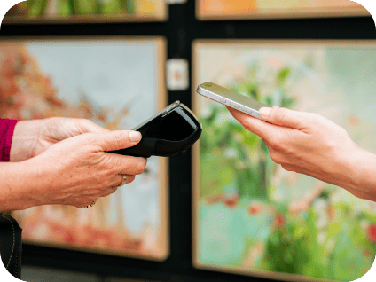 A person uses a smartphone to make a contactless payment at a handheld card terminal.