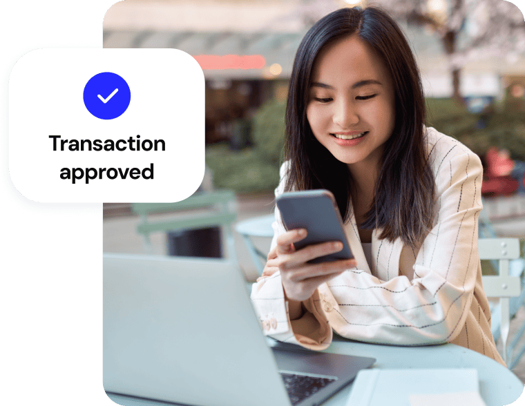 Woman looking at her phone with a "Transaction approved" checkmark notification overlay.