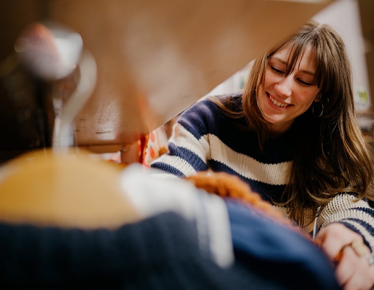 Woman smiling and placing something on a shelf in a retail store