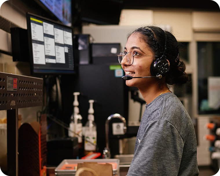 An image of a person wearing a headset reviewing orders on a kitchen display system.