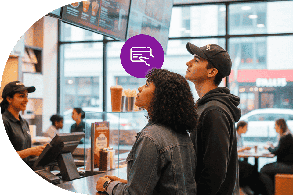 Quick service restaurant customers view menu items at a counter before ordering.