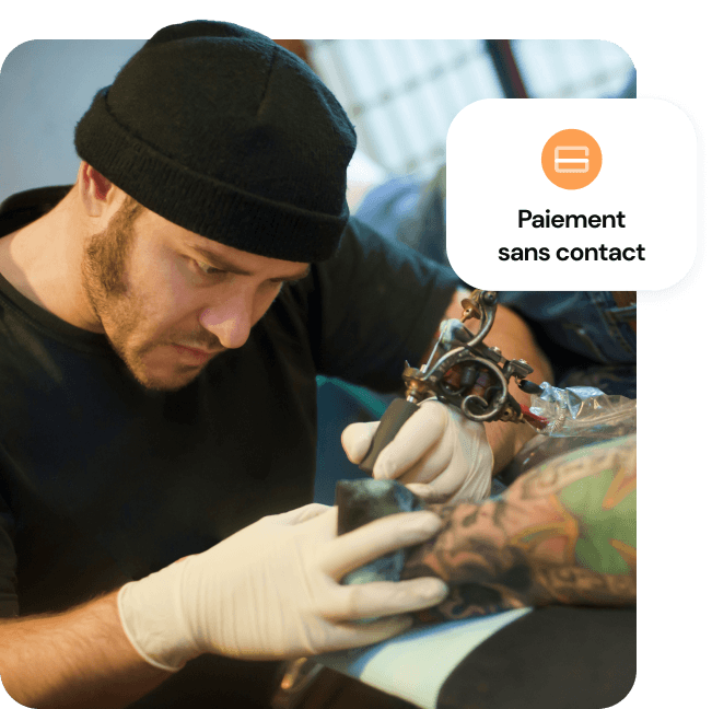 Un tatoueur applique de l'encre sur l'avant-bras d'un client, avec une mention « Payer sans contact » indiquant la possibilité de paiement.