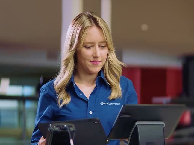 Retail worker operating a point-of-sale terminal at a checkout counter.