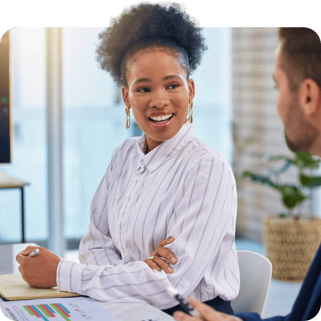 Professional woman smiling while listening to a colleague during a meeting.