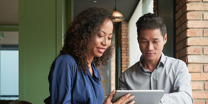 Man and woman looking at a tablet screen together in a modern office.
