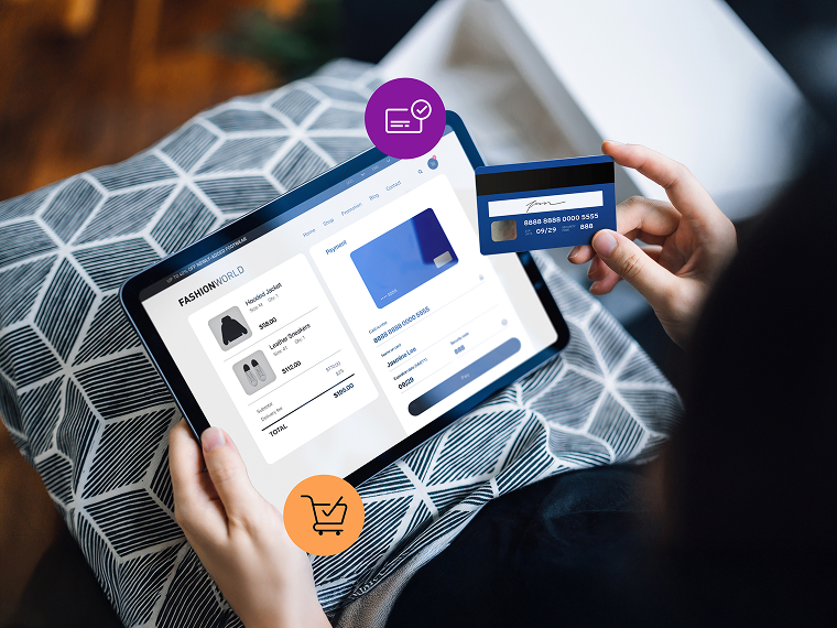 A person holds a tablet in one hand and a credit card in the other. They’re entering payment information to complete checkout online.